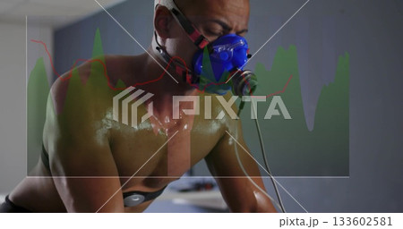 Cycling adult male leaning over bike handlebars in clinical lab, with mask tubing electrodes graph 133602581