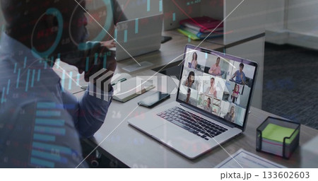 Talking African American man holding smartphone checking laptop online meeting at desk with binders 133602603