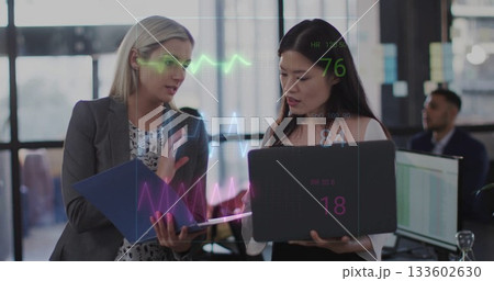 Colleagues reviewing holographic health metrics while holding blue folder and laptop in office 133602630