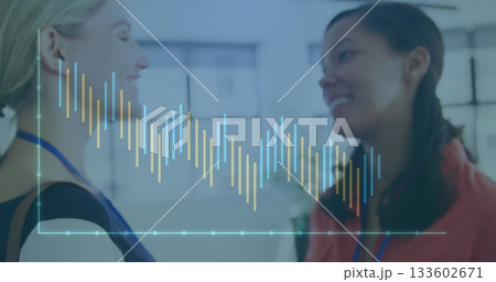 Discussing business women displaying digital bar chart overlay in office, with blue lanyards 133602671