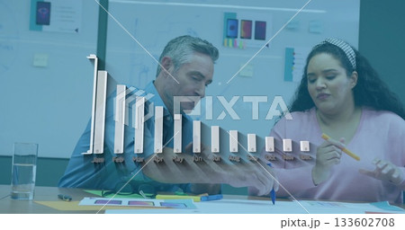 Analyzing colleagues reviewing printed charts and color swatches in office, with bar chart overlay Analyzing colleagues reviewing printed charts and color swatches in office, with bar chart overlay 133602708