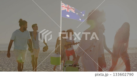 Walking eight friends hauling coolers, football, guitar on beach at sunset, with Australian flag 133602790