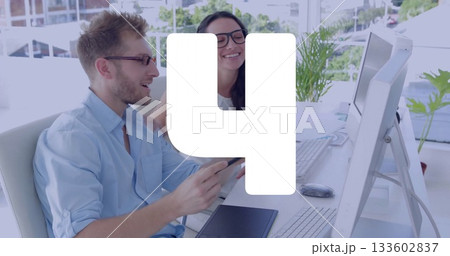 Smiling bearded man and woman reviewing tablet at desk, with monitors, potted plants, copy space 133602837