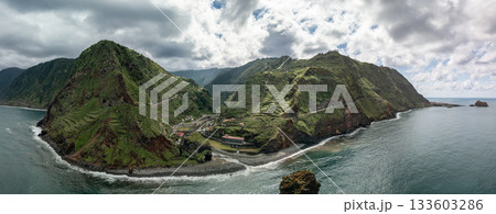 Panoramic drone view of the Ribeira da Janela coast on Madeira north shore, showing terraced green mountains, winding roads and the small seaside village Panoramic drone view of the Ribeira da Janela coast on Madeira north shore, showing terraced green mountains, winding roads and the small seaside village 133603286