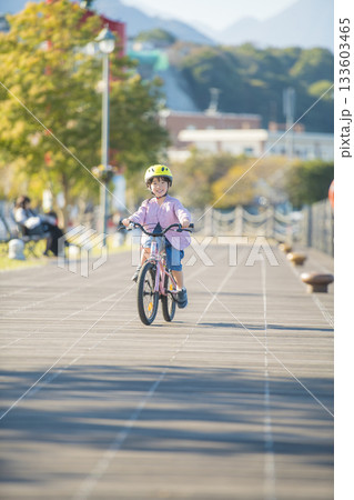 木製デッキを走る園児の女の子と明るい秋の屋外サイクリング風景 木製デッキを走る園児の女の子と明るい秋の屋外サイクリング風景 133603465