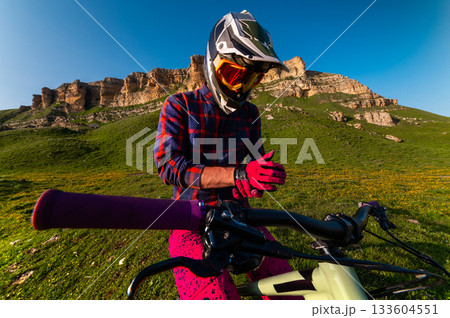 cyclist in special gear stands and adjusts his gloves. His gloved hands grip the handlebars. The athlete puts on clothing that will protect him in the event of a fall cyclist in special gear stands and adjusts his gloves. His gloved hands grip the handlebars. The athlete puts on clothing that will protect him in the event of a fall 133604551