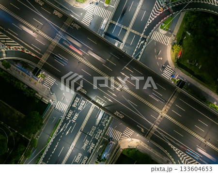 Aerial view of a busy highway intersection at night in an urban area, with moving car light trails. 133604653