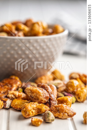 Nuts coated in sugar glaze on white table. Nuts coated in sugar glaze on white table. 133606655