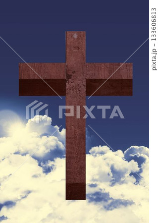 Wooden cross standing against deep blue sky with shining sunlight and glowing clouds in flat design 133606813