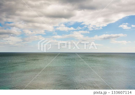 Calm ocean surface is being shown with horizon line in flat design and scattered clouds 133607114