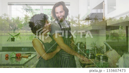 Embracing cooking couple stirring frying pan on stovetop at kitchen island, with tomatoes and herbs 133607473