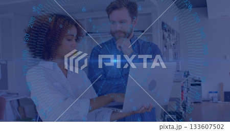 Two professionals analyzing data on laptop in modern office, with blue HUD overlay and shelving 133607502