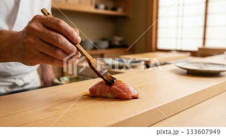 寿司職人が大トロの握りに煮切り醤油を塗る手元 133607949