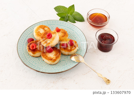 Curd fritters with raspberries, strawberry jam and honey. Curd fritters with raspberries, strawberry jam and honey. 133607970