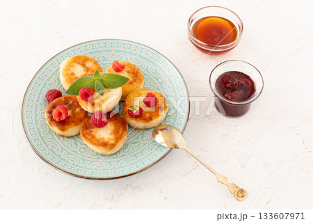 Curd fritters with raspberries, strawberry jam and honey. Curd fritters with raspberries, strawberry jam and honey. 133607971
