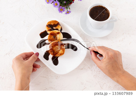 Curd fritters with chocolate on the porcelain plate and a cup of coffee. 133607989