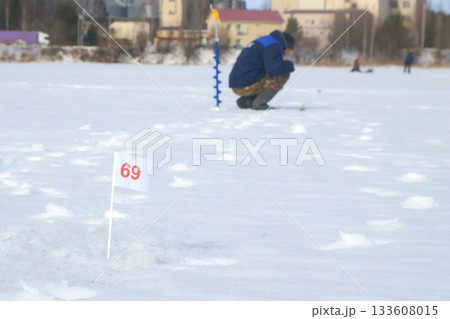 Fisherman waiting for fish biting on frozen lake on catching fish competition. Fisherman waiting for fish biting on frozen lake on catching fish competition. 133608015