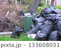 Black garbage bags near and an overturned trash can on the street. 133608031