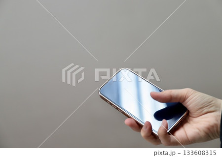 中年女性が右手に持ったスマートフォン 133608315