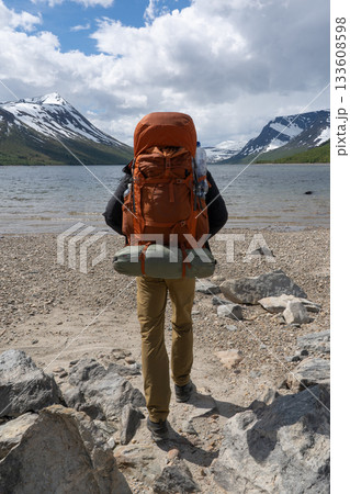 Hiker with heavy backpack walking towards Gjevilvatnet lake, Norway 133608598