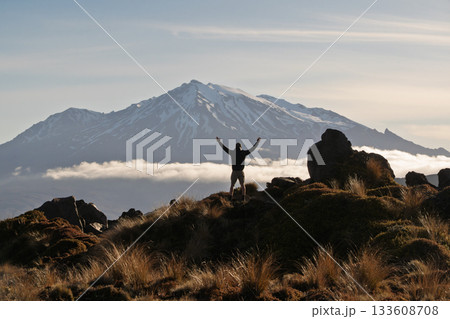 Hiker celebrating with arms raised facing Mount Ruapehu volcano, NZ Hiker celebrating with arms raised facing Mount Ruapehu volcano, NZ 133608708