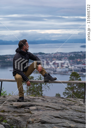 Hiker sitting on bench overlooking Trondheim from Vattakammen, Norway Hiker sitting on bench overlooking Trondheim from Vattakammen, Norway 133608722