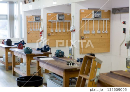 Wooden workbenches featuring bench grinders and loose cables are lining flat design workshop room Wooden workbenches featuring bench grinders and loose cables are lining flat design workshop room 133609096