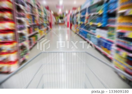 Shopping cart in motion amidst product on shelves for sale 133609180