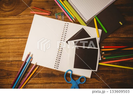 Flat design scene is showing spiral notebook on wooden desk with colored pencils, crayons, scissors 133609503