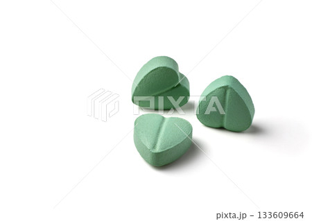 Turquoise heart-shaped cardiology pills isolated on white background. 133609664