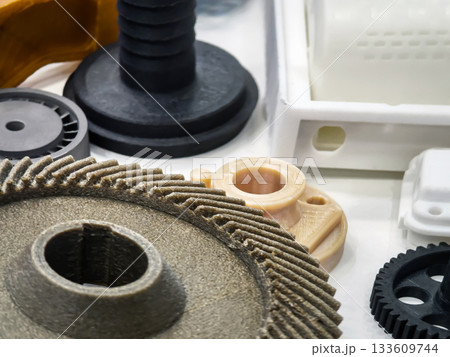 Close-up of various 3D printed components showcasing intricate designs and diverse materials on a white background 133609744