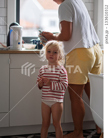 Little girl standing in the kitchen trying to get her mother attention 133610312