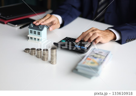 Investing in Real Estate, Real estate agent or investor calculating, planning, analyzing financial data for property investment. Themes of saving, investing, financial aspects of purchasing a home. Investing in Real Estate, Real estate agent or investor calculating, planning, analyzing financial data for property investment. Themes of saving, investing, financial aspects of purchasing a home. 133610918