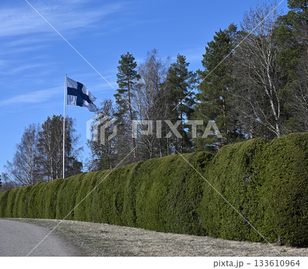 the Finnish flag waving proudly on a tall flagpole against a vibrant blue sky 133610964