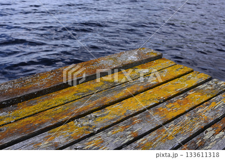 the vivid textures and colors of a weathered wooden dock at the edge of a lake the vivid textures and colors of a weathered wooden dock at the edge of a lake 133611318