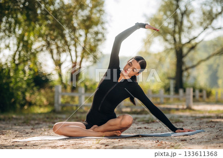 Healthcare concept, doing exercises. Young sportive skinny woman is in black fitness clothes outdoors 133611368