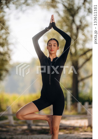 Young sportive skinny woman is in black fitness clothes outdoors 133611381