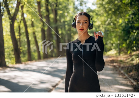 Young sportive skinny woman is in black fitness clothes outdoors Young sportive skinny woman is in black fitness clothes outdoors 133611427