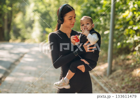 Boy is with an apple. Mother with her little son is outdoors. In sportive clothes 133611479