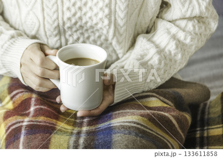 ブランケットをかけてカフェオレを飲む女性の手元（冬） 133611858