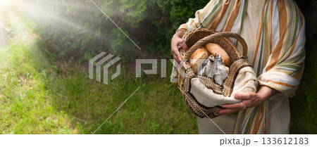 Man holding a basket with fish and bread 133612183