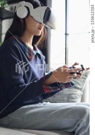 Woman play games wearing virtual reality glasses in the living room. Woman play games wearing virtual reality glasses in the living room. 133612383