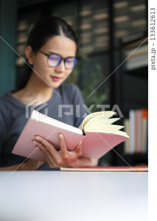 Happy Beautiful Asian Women Reading Book on Desk. 133612613