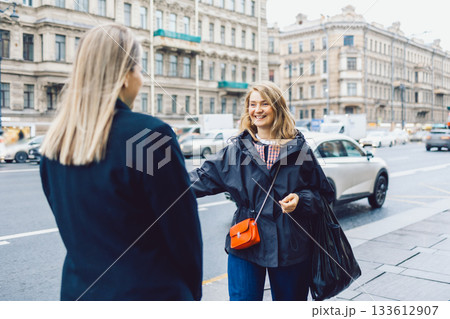 Two female friends met and joyfully hugged each other Two female friends met and joyfully hugged each other 133612907