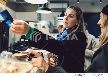 woman pays for coffee with card in cafe 133612940