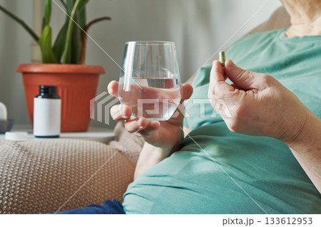 Senior woman with overweight taking daily medicine or supplement with a glass of water at home Senior woman with overweight taking daily medicine or supplement with a glass of water at home 133612953