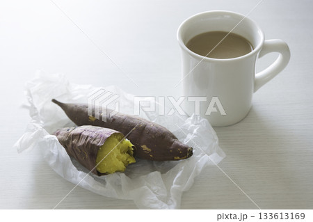 白いテーブルに置かれた焼き芋とマグカップのカフェオレ 133613169
