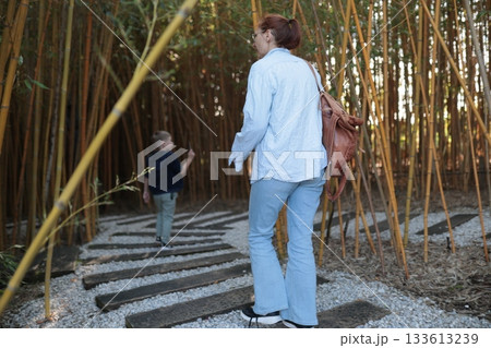 Woman and boy exploring bamboo forest path together 133613239