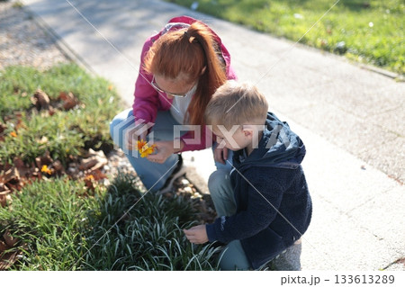 Mother and child exploring nature, discovering colorful flowers Mother and child exploring nature, discovering colorful flowers 133613289