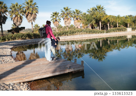 Woman and child enjoying time together by lake 133613323